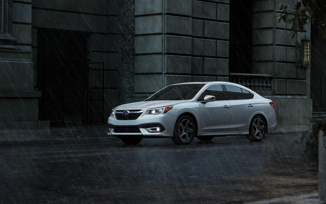 A 2022 Subaru Legacy driving on a rainy city street.